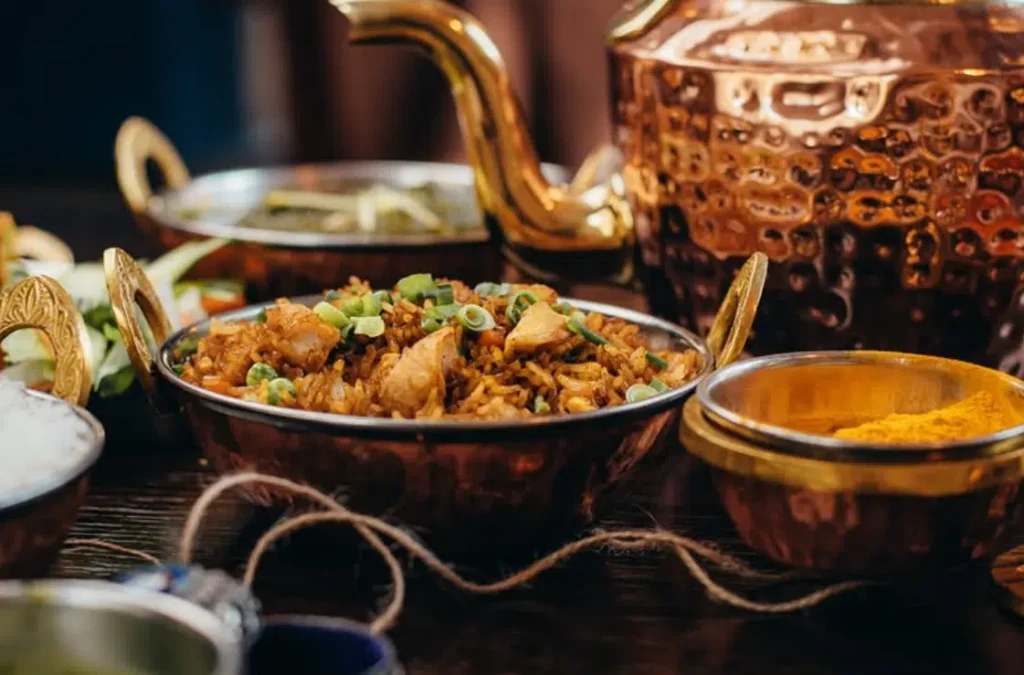 Spiced fried rice served in a copper bowl alongside traditional teapots.