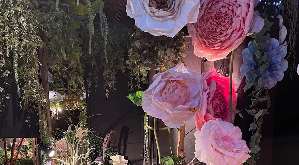 Giant paper flowers and hanging greenery inside the Fairy Valley exhibition space.