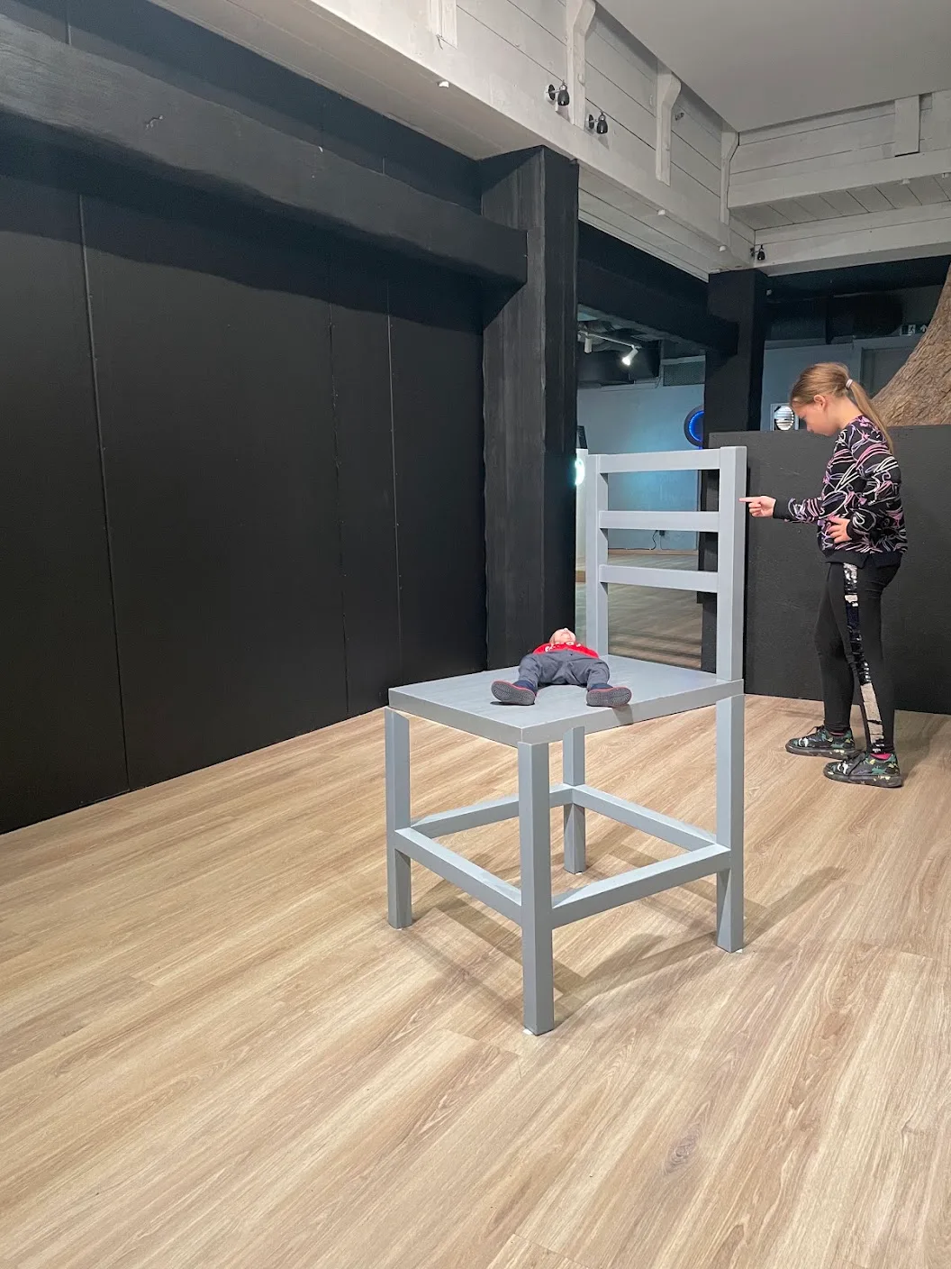 A child lying on a giant chair exhibit at the Museum of Illusions.