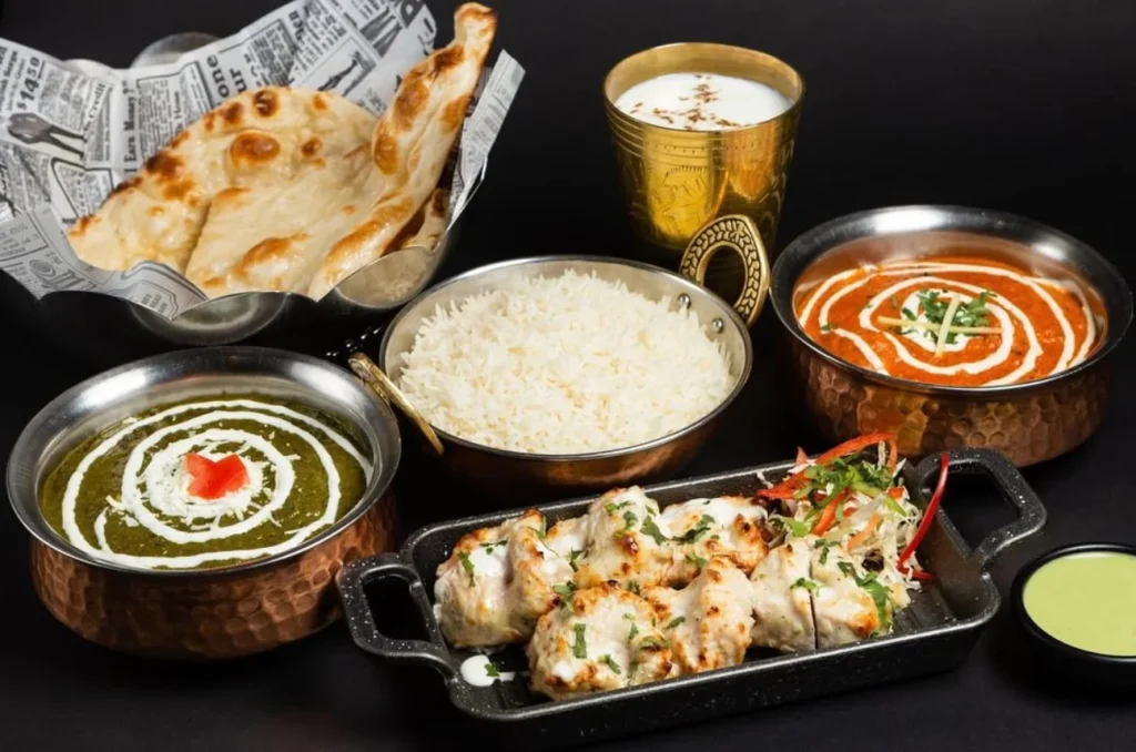 Assorted Indian dishes including curries, rice, naan, and tandoori chicken.