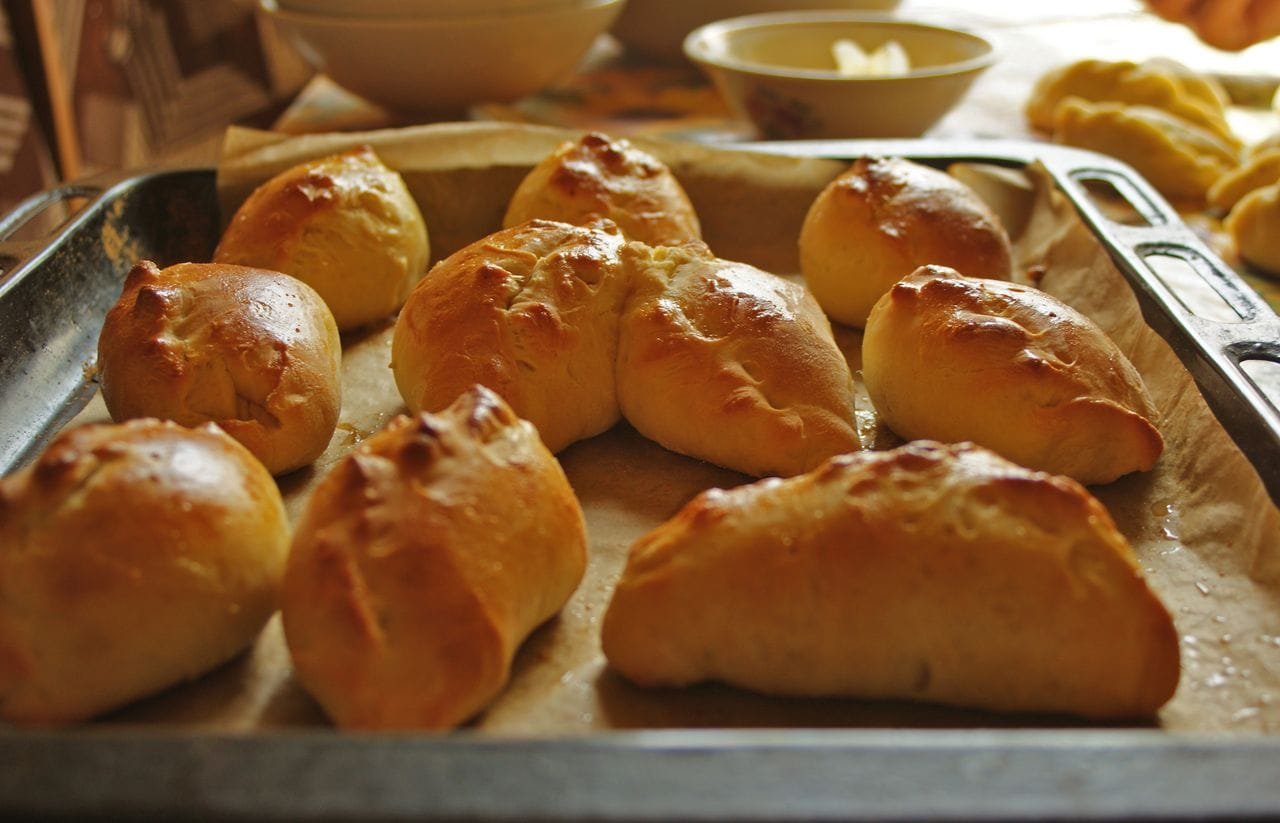 Freshly baked kibinai pastries on a baking sheet – popular food for day trips from Vilnius.