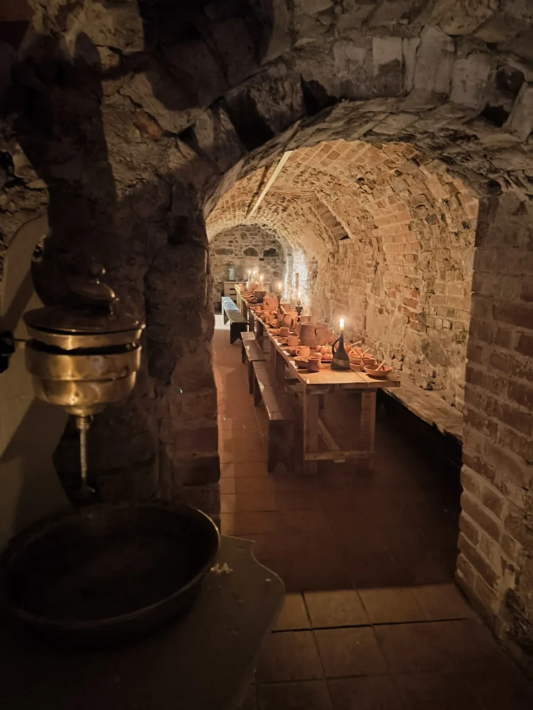 Long candlelit wooden table inside the vaulted cellar of Tytuvėnai Monastery.