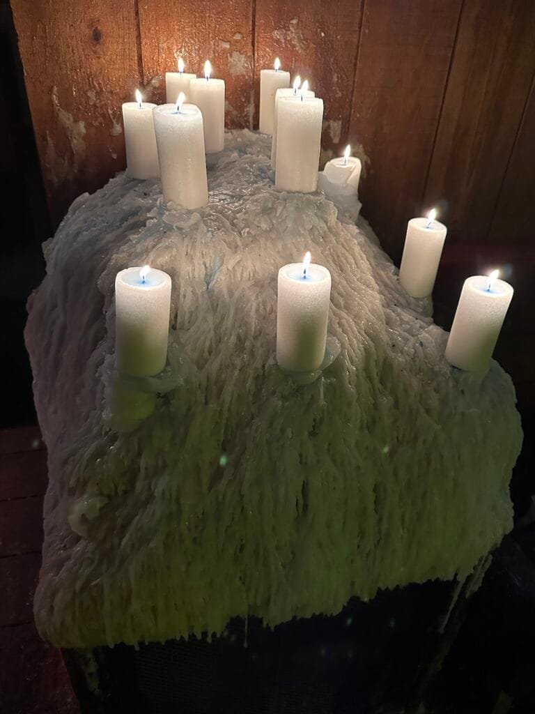 Lit white candles placed on a thick mound of melted wax for Vėlinės.
