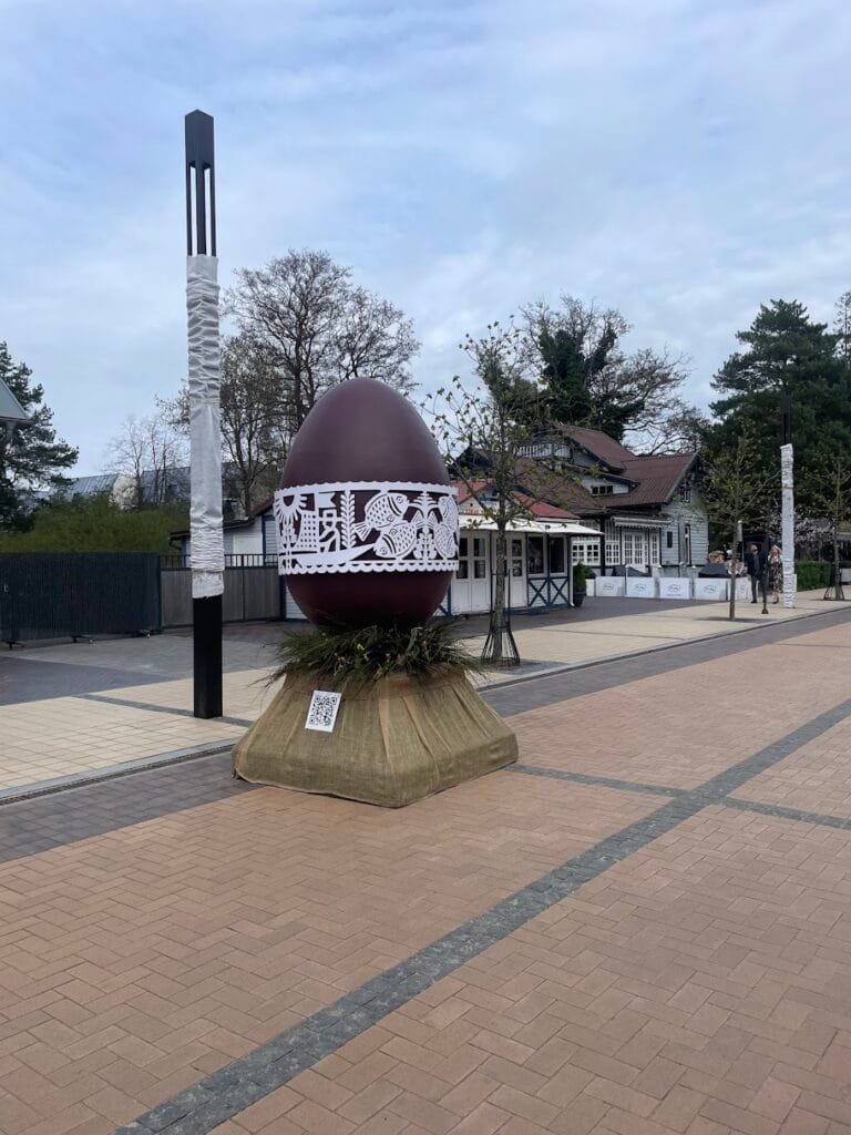 Giant decorated Easter egg sculpture displayed in a public pedestrian street.