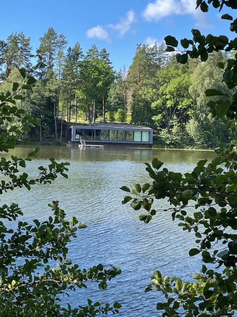 Modern house with glass windows located on the shore of a forest lake in Lithuania