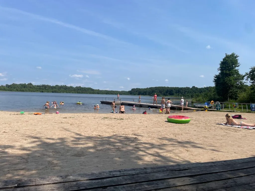 People swimming and relaxing at a sandy lake beach in Lithuania on a sunny summer day