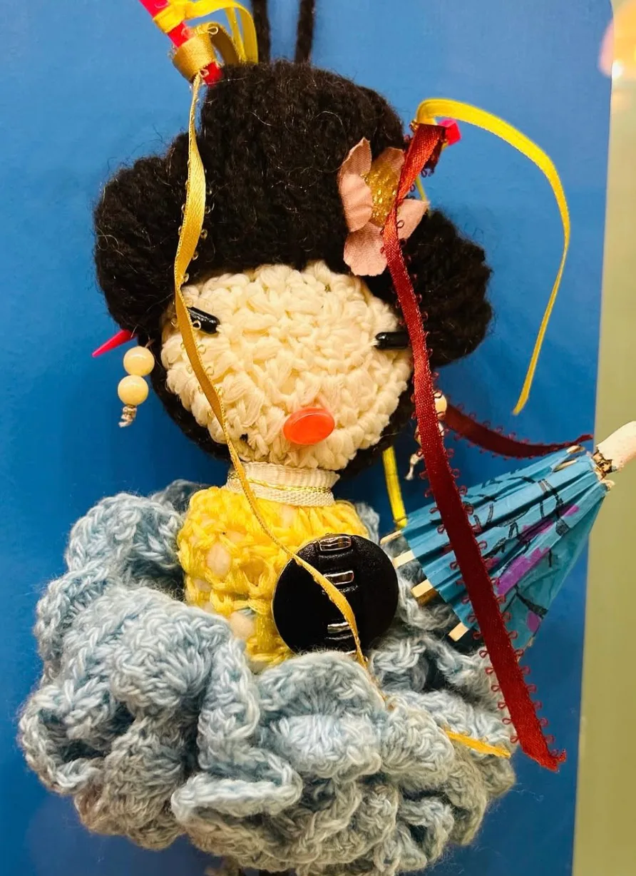 A handmade knitted doll holding a small umbrella at the Toy Museum.