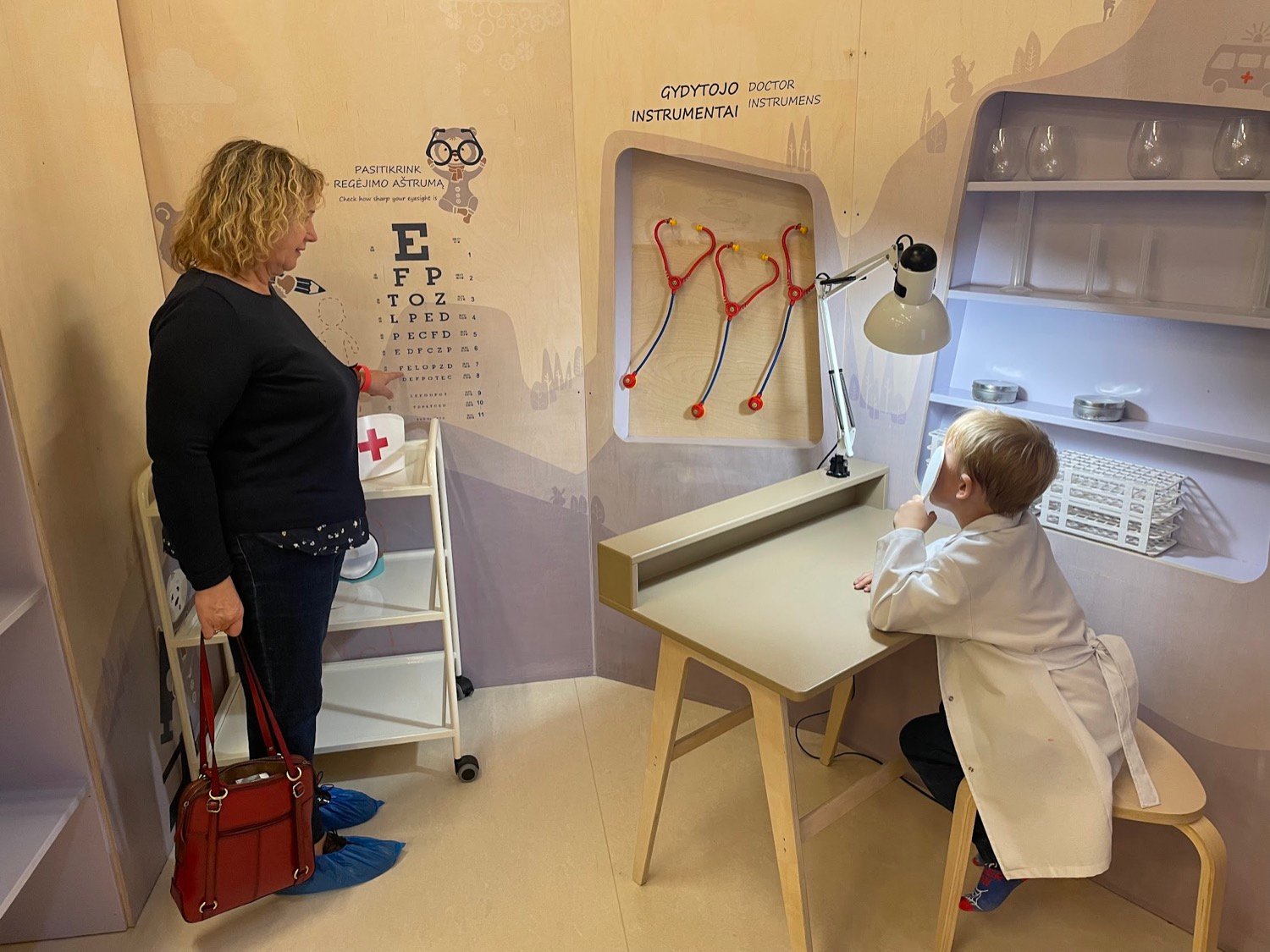 Child playing doctor with an adult testing vision at the Curio City educational play space.