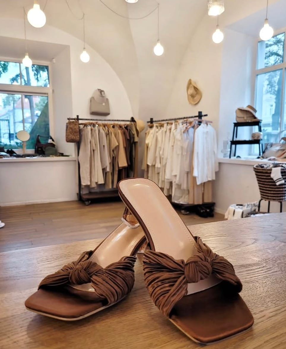 Brown mules on a table inside a bright vintage clothing and accessory store.