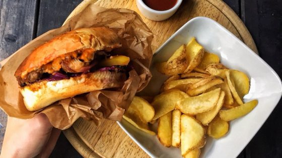 Juicy burger with crispy fries served on a wooden platter, a top pick from our best burgers in Vilnius guide.