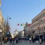Pedestrians exploring a busy historic street with unique architecture, showcasing one of the top things to do in Vilnius during the day.