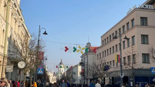 Pedestrians exploring a busy historic street with unique architecture, showcasing one of the top things to do in Vilnius during the day.