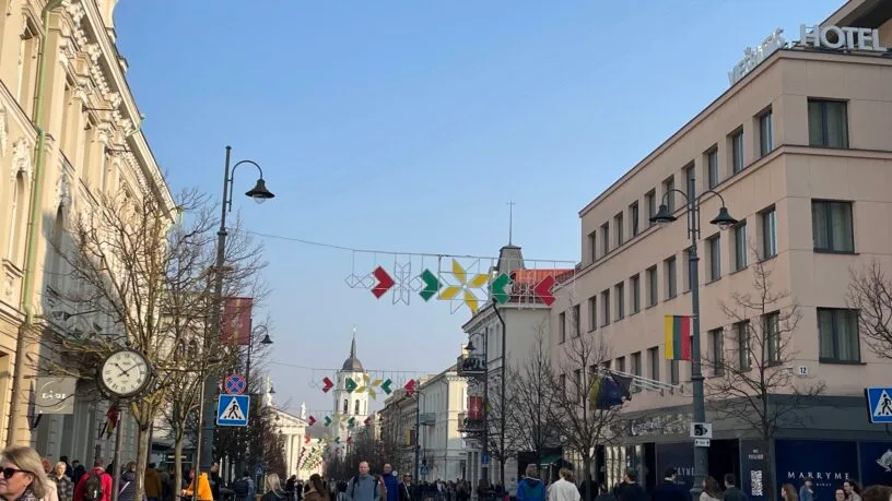 Pedestrians exploring a busy historic street with unique architecture, showcasing one of the top things to do in Vilnius during the day.