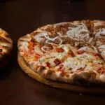 Two baked pizzas served on wooden boards for a guide on the best pizza in Kaunas.