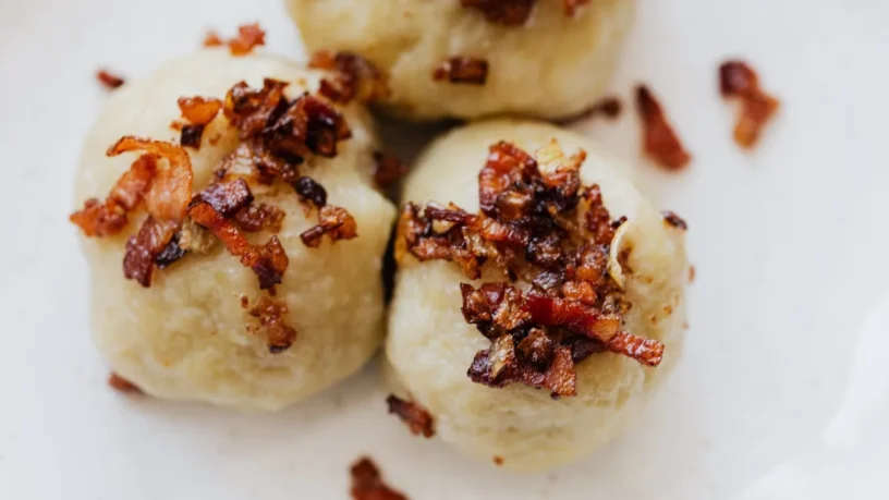 Traditional potato dumplings topped with bacon – a dish for Lithuania for foodies guide.
