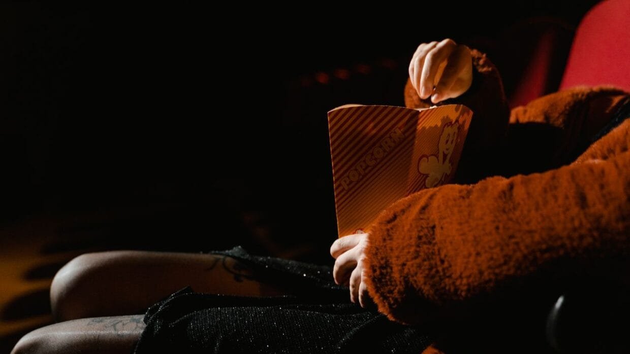 Person sitting in a cinema theater holding popcorn - Lithuanian movies in 2026.