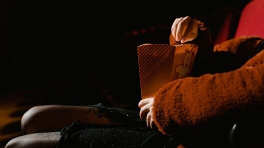 Person sitting in a cinema theater holding popcorn - Lithuanian movies in 2026.
