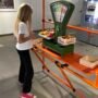 Girl playing with toy food scales at an interactive exhibit - museums in Kaunas for kids.