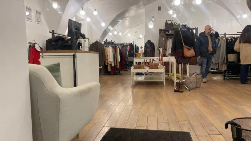 Bright and spacious interior of vintage clothing stores in Vilnius with racks and shoppers.